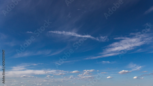 Wide view of deep blue sky filled with delicate cirrus clouds and scattered fair-weather clouds. Natural atmospheric background ideal for weather, climate, nature and environmental concepts.