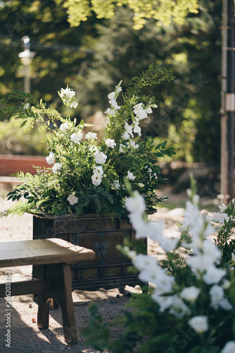Beautiful white wedding flower arrangement on traditional Korean wooden chest in outdoor garden
