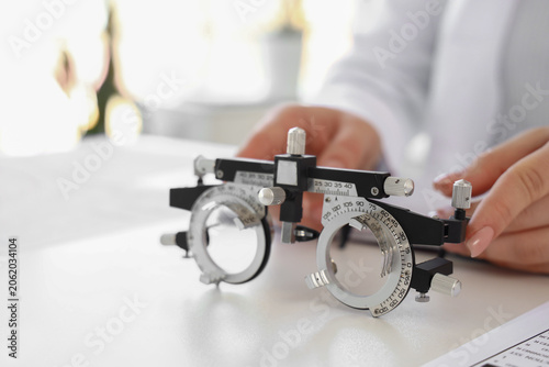 Female ophthalmologist with trial frame at desk in office, closeup
