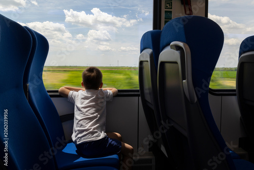 Quadro em tela A boy looks out the window of a train traveling through fields.