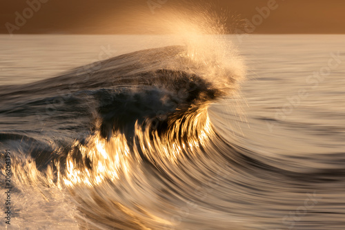 Foto Photograph of a powerful ocean wave breaking over a submerged reef at sunset on the south coast of New South Wales, Australia, captured with a slow shutter speed to create a dreamlike effect
