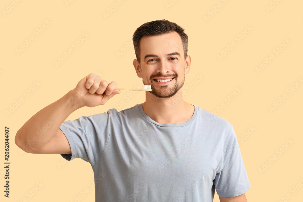 Fototapeta premium Handsome man with toothbrush on beige background