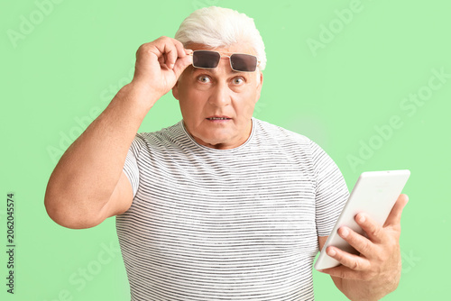 Shocked senior man with tab...