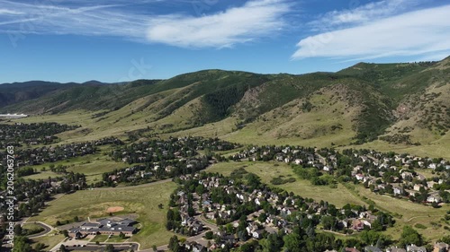 Wide Aerial of Ken Caryl Valley neighborhood in summer in Littleton Colorado with single family homes nestled among green fields and large forested mountainsides