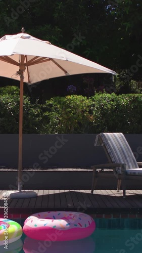 Vertical video: Panning camera revealing light patio umbrella moving left on deck, showing floats
