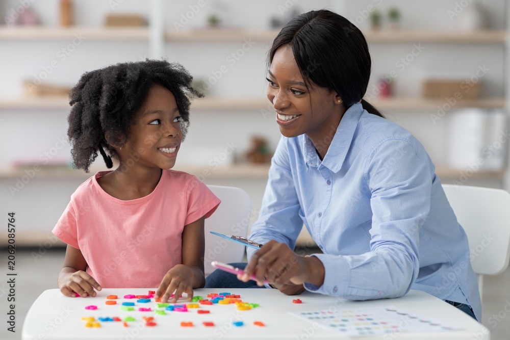 Fototapeta premium Smiling Black Mother With Daughter Playing Together With Colorful Building Blocks At Home, Encouraging Creativity And Bonding In A Cheerful Atmosphere. Family Lifestyle Concept.