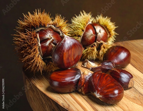 A still life of shiny brown chestnuts on a wooden surface