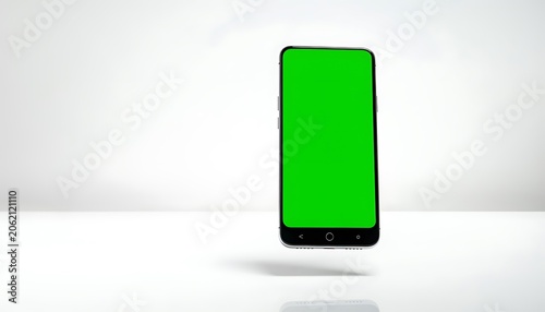 A smartphone displays green screen on white table indoors