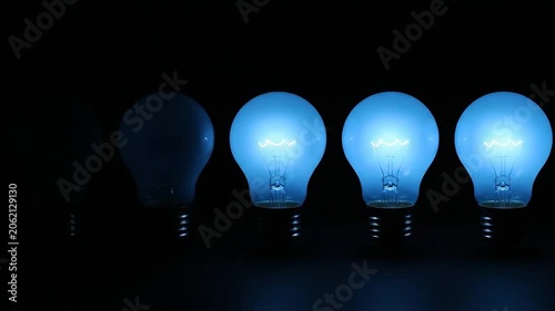 Row of glowing blue light bulbs illuminating a dark background