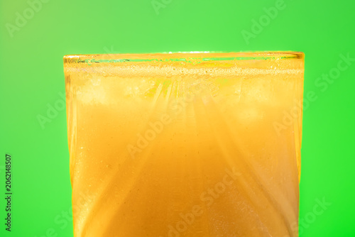 Canvas-taulu Faceted glass detail with orange juice and chroma green background