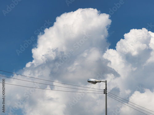 Streetlights against a blue, cloudy sky; streetlight poles are commonly found in urban or rural landscapes for illumination.