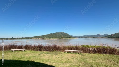 Scenic river viewpoint with benches and mountains under blue sky