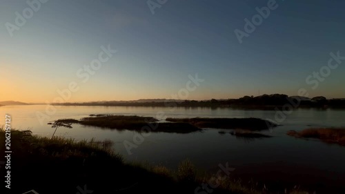 Sunset panning shot across peaceful Mekong River at dusk