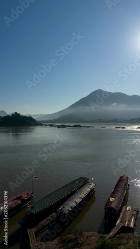Vertical view of traditional boats docked on misty Mekong River at Kaeng Khut Khu, Thailand 