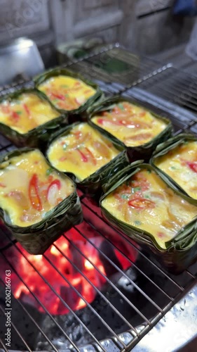 Thai grilled egg in banana leaf cups over charcoal grill