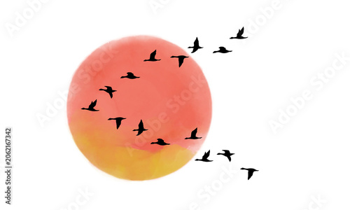 夕日をバックにV字型に飛ぶ鳥の群れのシルエット
