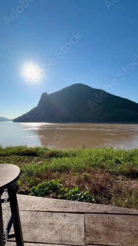 Iced black coffee on wooden stool overlooking river and mountains