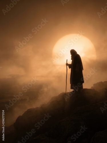 A dark silhouette of Abraham looking toward the promised land with a massive glowing sun behind him low on the horizon in thick atmospheric fog

