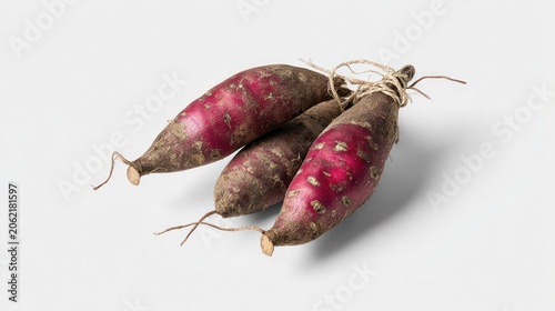 Three raw, unpeeled root vegetables tied together with twine rest upon a clean white surface