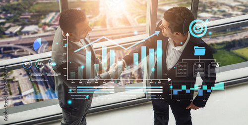 Tableau sur toile Business partnership meeting with data visualization and graphs representing growth and success in corporate environment with sunlight shining through glass s Haptic
