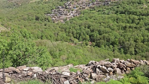 Traditional stone village nestled on a spring mountain hillside, surrounded by lush green trees and rocky peaks under clear blue sky.
📍 Kamalla village, Hawraman Takht, Kurdistan 
