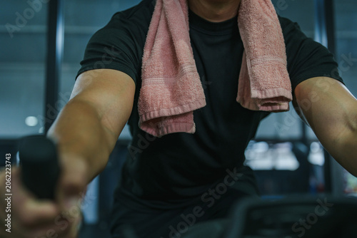 Billede på lærred Cropped view of man exercising on stationary bike in gym for intense cardio work