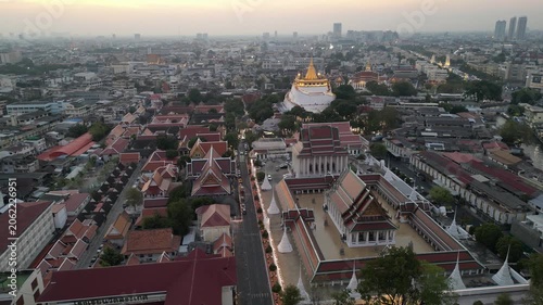 Aerial view of the illuminated Wat Saket temple and Golden Mount chedi surrounded by the urban landscape at dusk in Bangkok, Bangkok, Thailand.