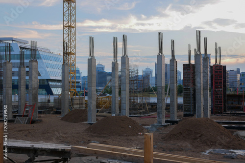 Concrete pillars rise from a dusty construction site