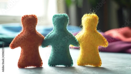 Three colorful felt dolls standing together on a gray surface