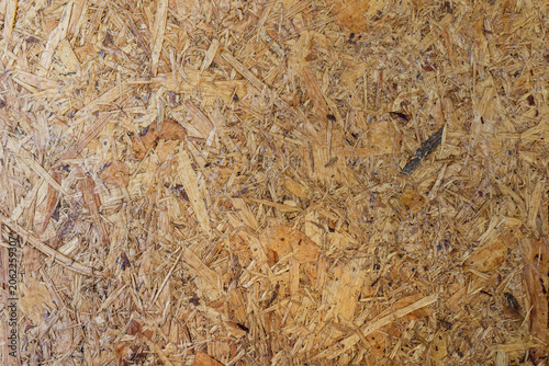 Texture of Oriented Strand Board (OSB) for Construction. High-resolution close-up of OSB showing compressed wooden flakes and chips, ideal for construction textures and industrial backgrounds.