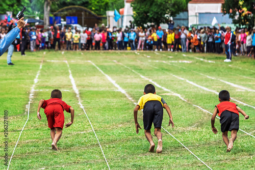 Foto Schoolboys starting barefoot running race with referee firing pistol