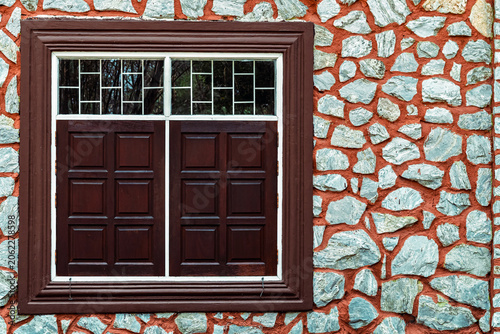 Vintage building facade with stone wall and wooden windows. Exterior view of vintage building featuring beautifully textured stone masonry wall. traditional wooden panel windows with white frames.