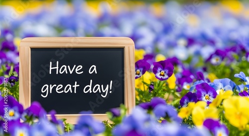 Small blackboard with have a great day text amidst colorful flowers.