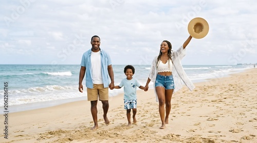 Happy African, American family walking together on beach vacation holding hands, summer seaside lifestyle
