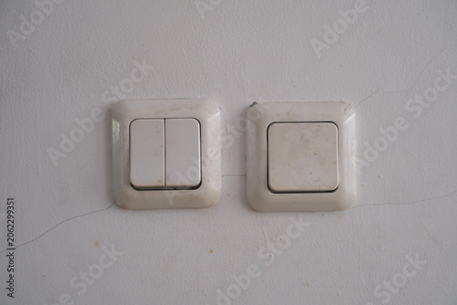Foto Close up of old white plastic light switches on a cracked concrete wall