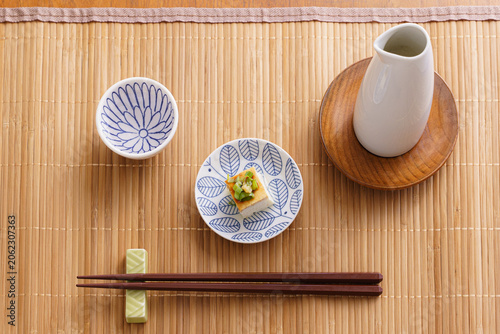 Japanese Sake Set with Chilled Tofu, Tokkuri, and Ochoko on a Bamboo Mat