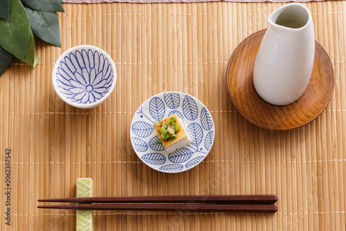 Japanese Sake Set with Chilled Tofu, Tokkuri, and Ochoko on a Bamboo Mat