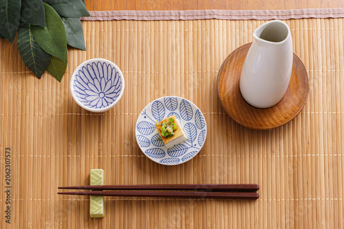 Japanese Sake Set with Chilled Tofu, Tokkuri, and Ochoko on a Bamboo Mat
