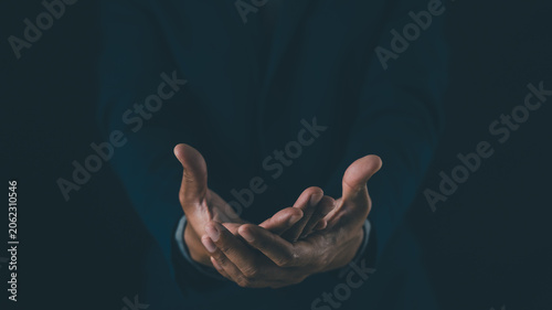 Fotografie Two open hands cupped together against a dark background, symbolizing offering, help, or receiving