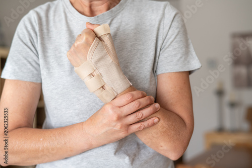 Photos Woman experiencing wrist joint pain and discomfort, wearing a therapeutic wrist