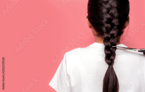 Картината върху платно Back view of Asian woman with braided hairstyle is cutting with scissors for donate to cancer patients