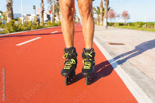 Photos Man's legs in inline skates moving along a red path near the beach