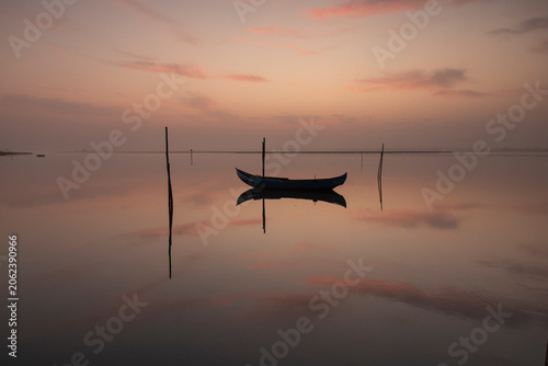 Schilderij op canvas Serene boat floating on reflective water at dusk