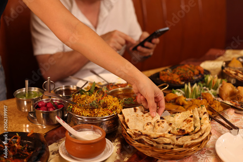 Foto Diner Reaching for Naan Bread at Traditional Indian Restaurant Table
