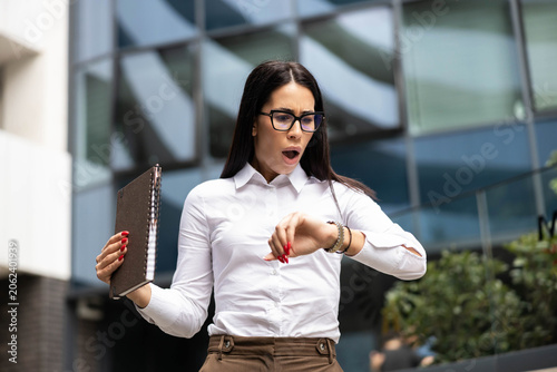 Canvas Print Business woman checking wrist watch feeling shocked, experiencing urgency and st