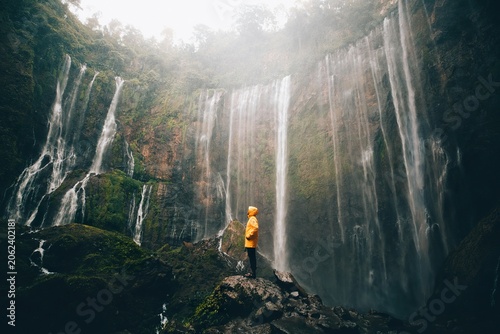 Fotografía Person in yellow jacket exploring waterfall and rocky landscape