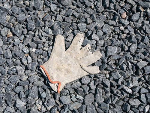 heavily worn and broken work glove lying on gravel outdoors