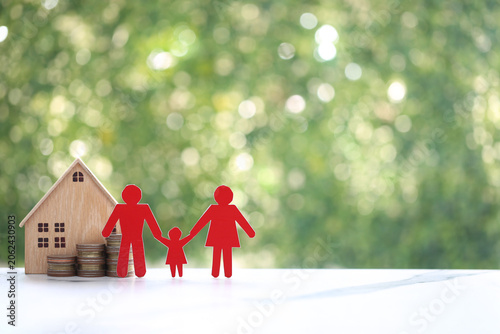 Red paper family and a wooden house model on coin stacks, symbolizing family housing security, mortgage planning, real estate investment and financial protection for homeownership.