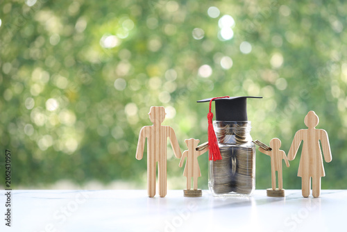 Wooden family figures standing with a jar of coins topped with a graduation cap, symbolizing education savings, college fund planning, financial investment for children and academic future.