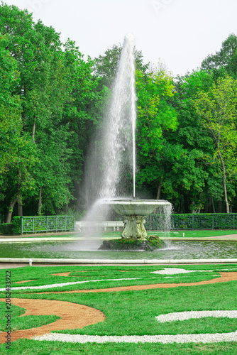 Fountain sprays water in green park on sunny day